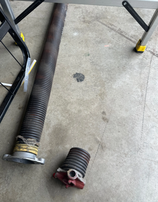 a professional technician performing a garage door spring repair on a residential property in Orlando, FL, showcasing the tools and expertise used by Orlando FL Quick Garage Door and Gate Repair."