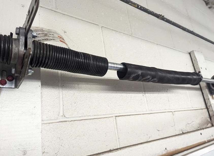 "Close-up image of a technician performing a garage door spring repair, showcasing the tools and techniques used by Orlando FL Quick Garage Door and Gate Repair to ensure efficient and reliable service."